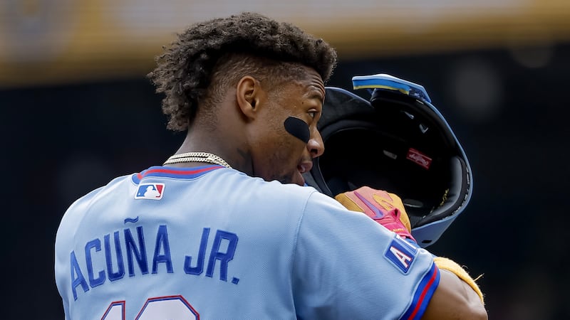 Atlanta Braves' Ronald Acuna Jr. adjusts his helmet while standing on third base against the...