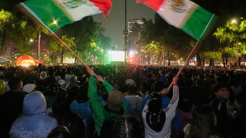 Mexican fans wave flags as they watch the World Cup round of 32 soccer match between Mexico...